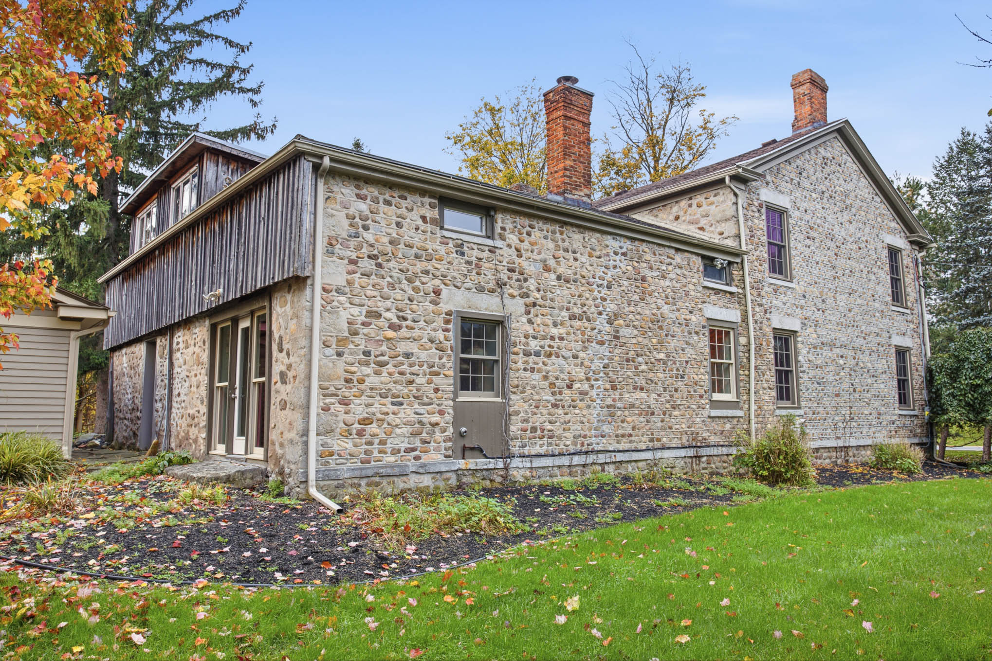 Angled exterior view of the cobblestone home and wood-sided wing
